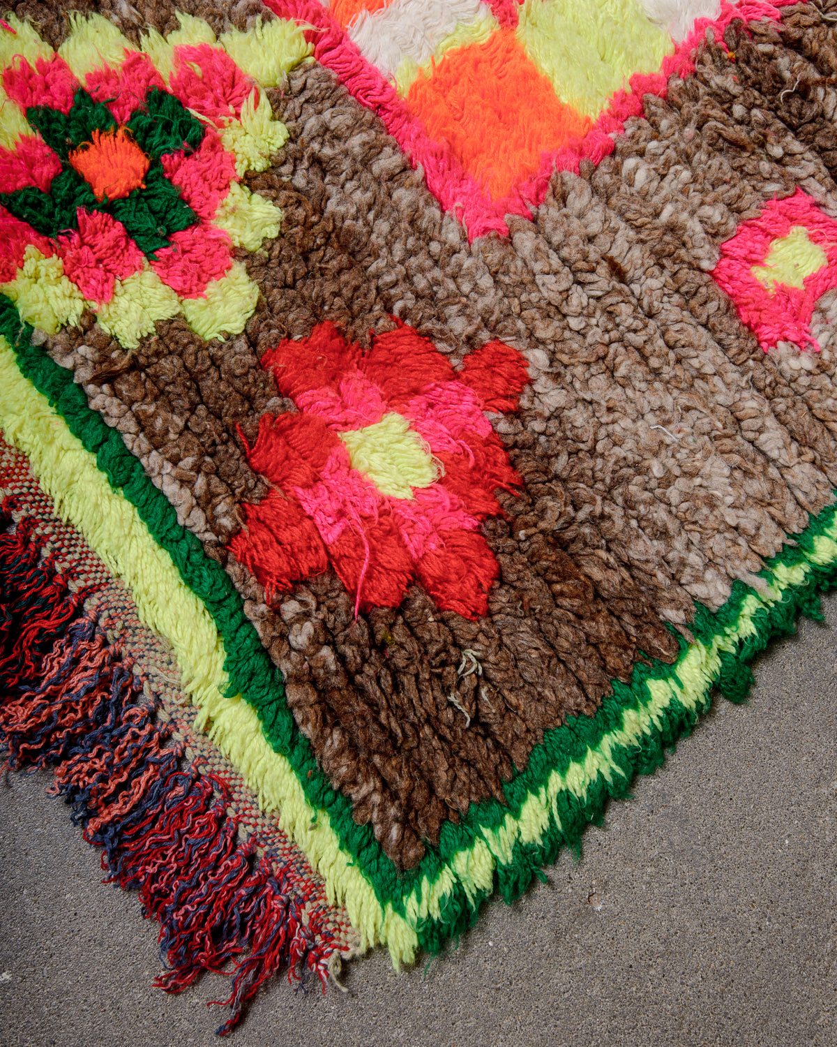 Corner of vintage runner rug with cotton tassels.